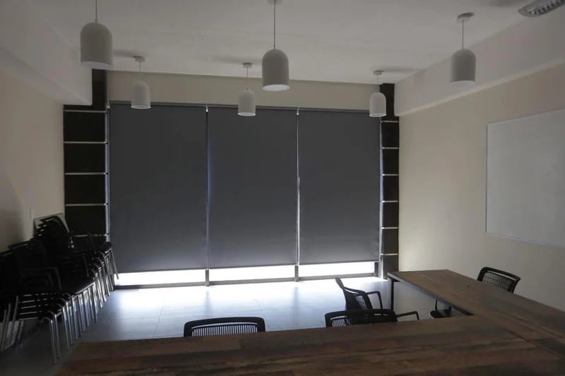 Persianas enrollables en una sala con mesas y sillas.